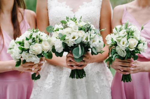 The bride and bridesmaids in an elegant pastel pink dress is sta